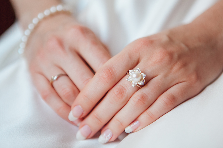 bride Hand with Diamond ring and pearl bracelet on white dress