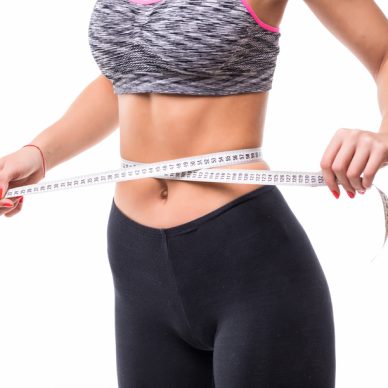 young fitness Woman measuring her body with ruler dressed in fasion sportswear losing weight concept