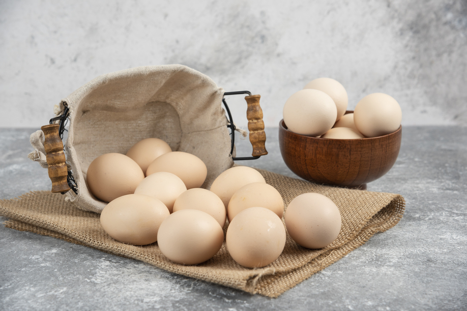 Basket and bowl full of organic fresh uncooked eggs on marble surface. High quality photo