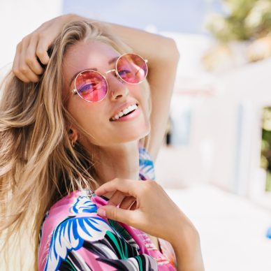 Close-up portrait of magnificent caucasian girl in round pink sunglasses. Lovable long-haired blonde woman enjoying life and having fun at resort.