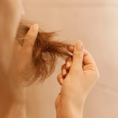 Closeup portrait of woman hands holding dry damaged hair eds, having trichology problem.