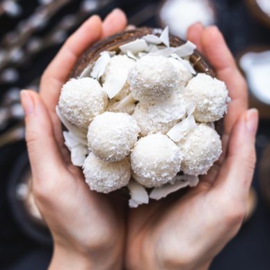 A closeup shot of a woman holding a bowl of delicious raffaello with a blurry background of ingredients