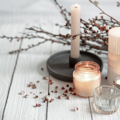 Cozy composition with flaming candles and young tree branches on a wooden surface in the Scandinavian style.