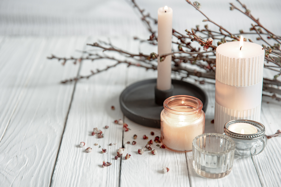 Cozy composition with flaming candles and young tree branches on a wooden surface in the Scandinavian style.