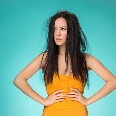 Frustrated young woman having a bad hair on blue