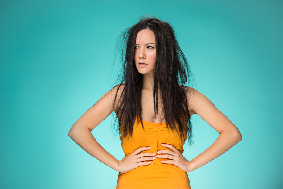 Frustrated young woman having a bad hair on blue