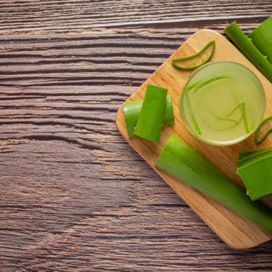 a glass of aloe vera  juice put on wooden cutting board