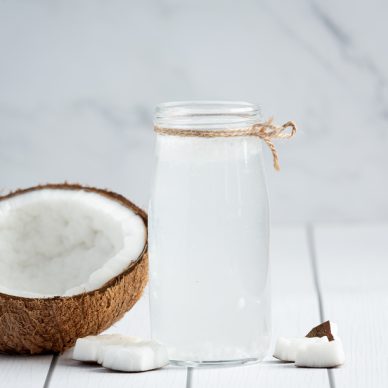 glass of coconut water put on white wooden background