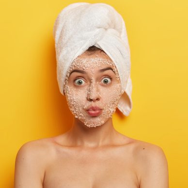 Headshot of beautiful Caucasian woman has widely opened eyes, keeps lips folded, cares about purity and freshness of skin, has surprised face expression, well cared body, takes shower in bathroom