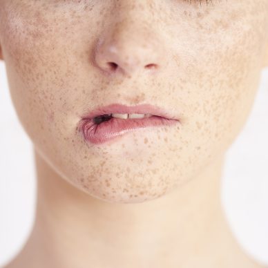 Part of woman biting her lip at studio shot