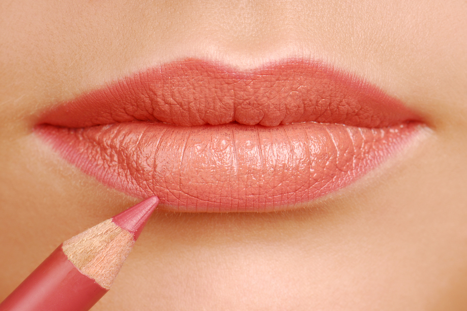 Red lipstick cosmetic pencil. Make-up tool. Woman lips close up