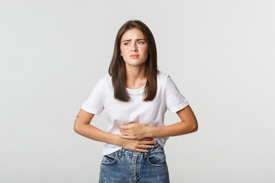 Woman having stomach ache, bending and holding hands on belly, discomfort from menstrual cramps.