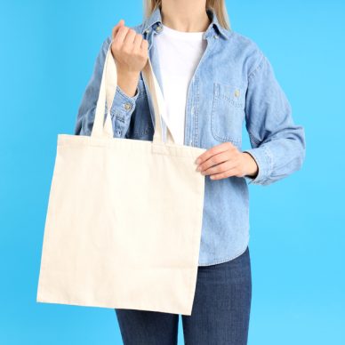 Woman holds white eco bag on blue background
