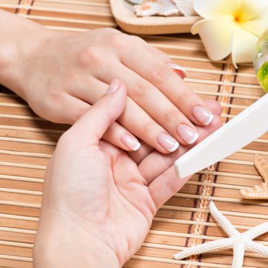 Woman in a nail salon receiving manicure by a beautician. Beauty treatment concept.
