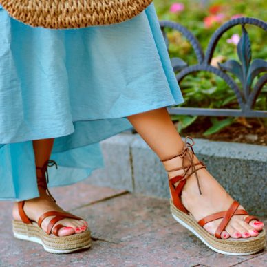 Close up fashion details of woman feetÕs, elegant gladiator sandals, blue feminine dress, perfect for summer vacation.