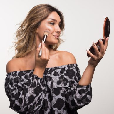 Young woman applying bronzer on white background. High quality photo