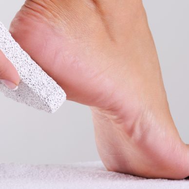 young woman scrubbing her foot by pumice in a beauty salon