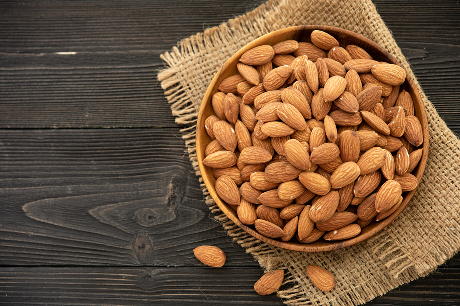 almond in a wooden bowl. on a wooden background, near a bag from burlap. Healthy food and snack, organic vegetarian food. (selective focus; close-up shot)