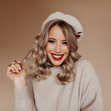 Appealing french lady playing with her long hair. Wonderful white girl in brown beret smiling to camera