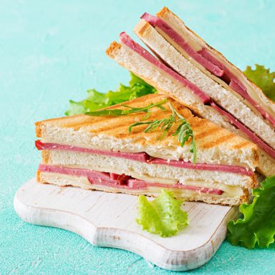 Club sandwich - panini with ham and cheese on light background. Picnic food.