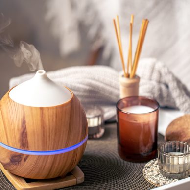 Oil diffuser on blurred background near candles. Aromatherapy and health care concept.
