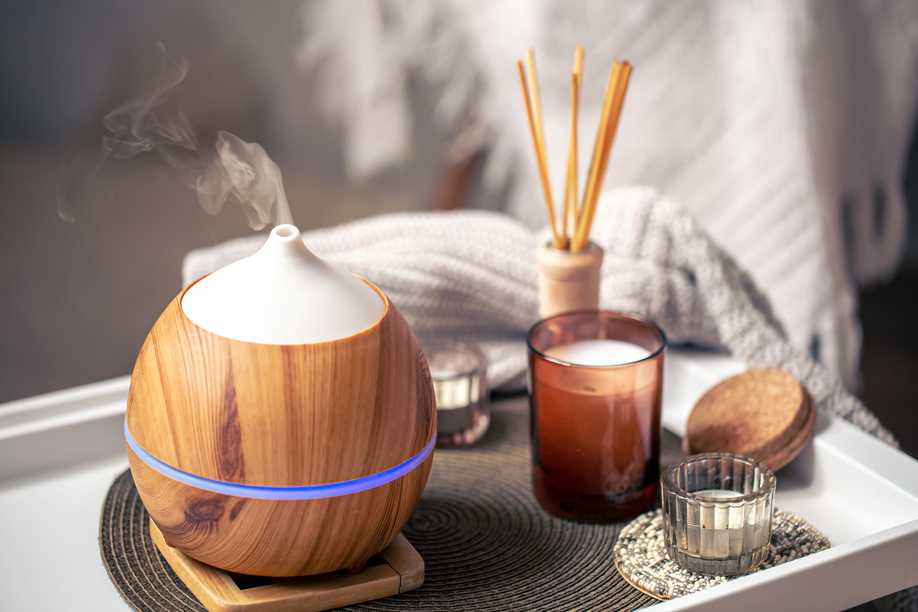 Oil diffuser on blurred background near candles. Aromatherapy and health care concept.