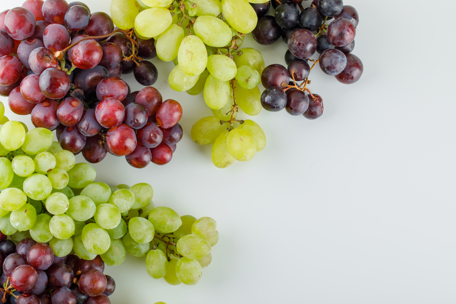 Different ripe grapes flat lay on a white background