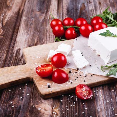 Fresh and healthy food. Delicious Italian dinner. Fresh cheese served on wooden board with arugula and cherry tomatoes on rustic wooden table