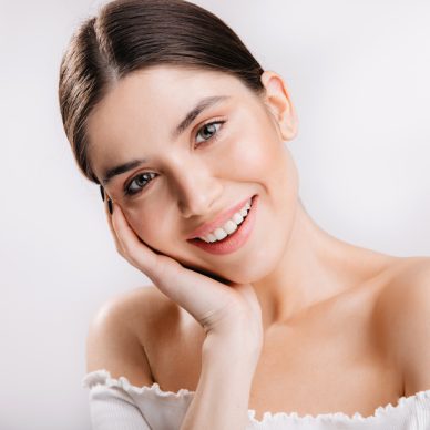 Portrait of smiling girl with healthy skin. Cute dark-haired woman looking at camera on white background