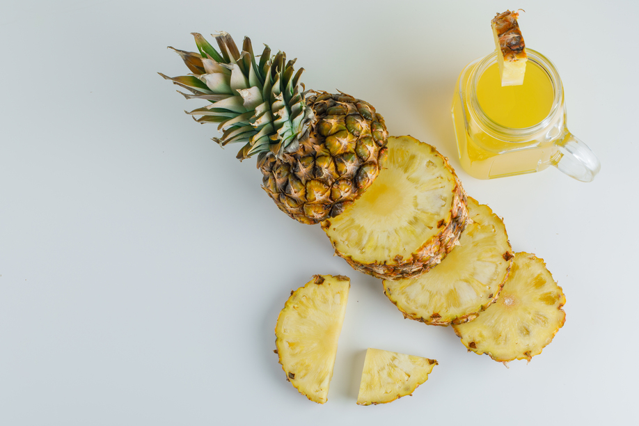 Sliced pineapple with juice flat lay on a white background