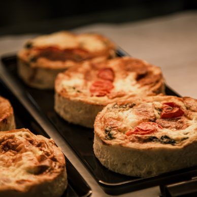 Small puff pies with vegetables and meat, quiches in a cafe window close up.