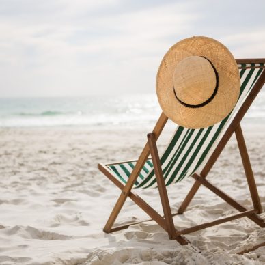 Straw hat kept on empty beach chair at tropical sand beach