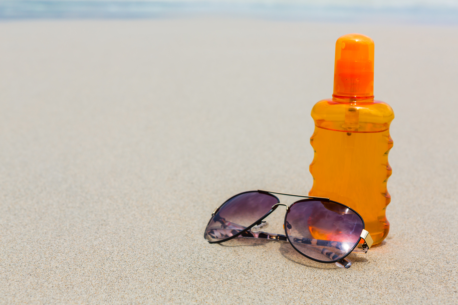 Sunscreen lotion and dark glasses on the beach for summer time