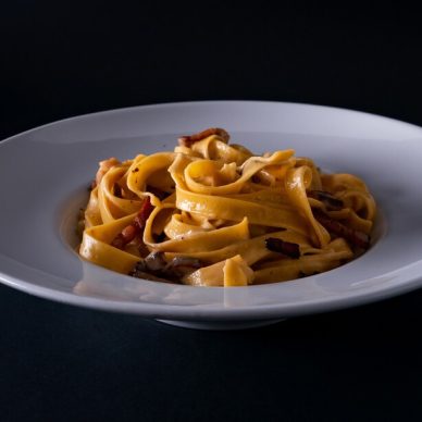 A vertical shot of a tagliatelle bolognese on black background