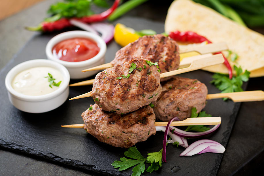 Appetizing kofta kebab (meatballs) with sauce and tortillas tacos on black background