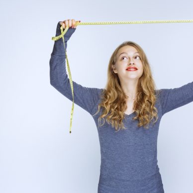 Blonde girl opening the measuring tape and showing the result. High quality photo