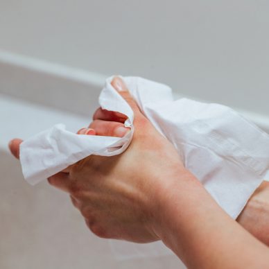 Close-up of woman using antibacterial wipe and cleaning hands in the bathroom.