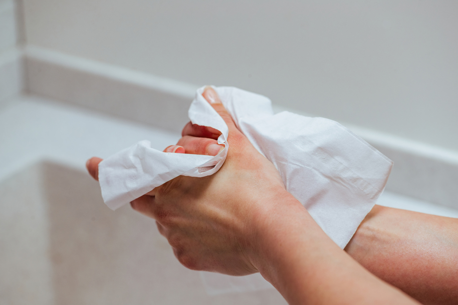 Close-up of woman using antibacterial wipe and cleaning hands in the bathroom.