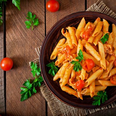 Penne pasta in tomato sauce with chicken and tomatoes  on a wooden table