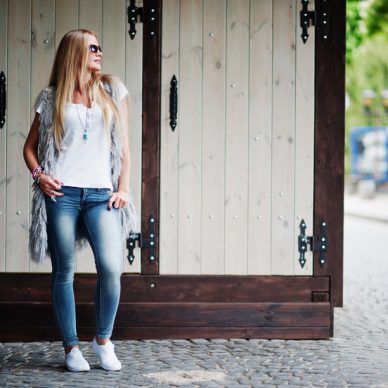 Stylish blonde woman wear at jeans and girl sleeveless with white shirt against street.