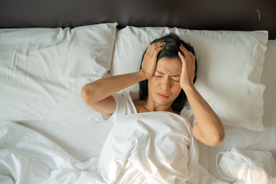 Unhappy exhausted mature woman with closed eyes lying in bed, touching temples close up, tired female suffering from headache or migraine, feeling unwell, suffering from insomnia, lack of sleep