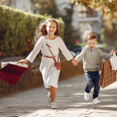 Beautiful girl in a summer city. Children with shopping bags. Boy in a gray sweater