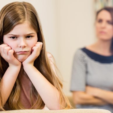 Daughter sitting upset with her mother in living room at home