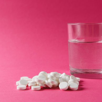 Medication pile white round tablets arranged abstract on pink rose color background. Aspirin, glass water pills for design. Health treatment choice healthy lifestyle concept. Copy space advertisement