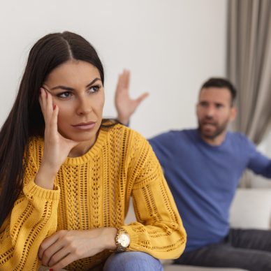 Young couple having argument - conflict, bad relationships. Angry fury woman. Angry young couple sit on couch in living room having family fight or quarrel suffer from misunderstanding