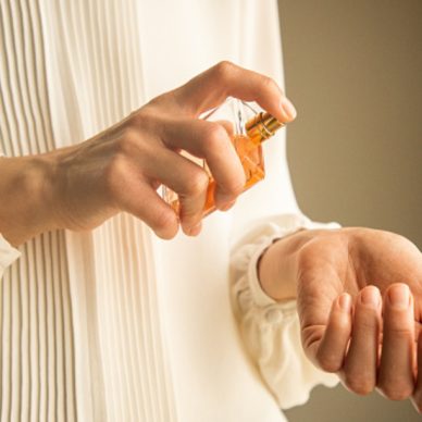 Classy look of young woman applying and testing perfume on her wrist