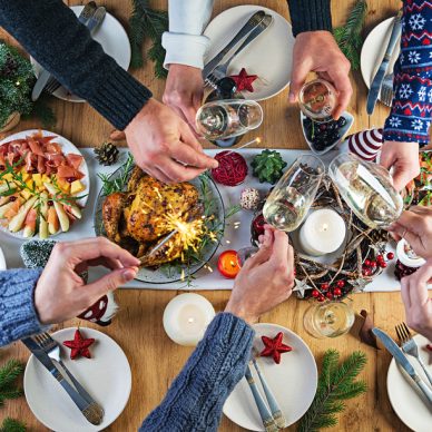 Baked turkey. Christmas dinner. The Christmas table is served with a turkey, decorated with bright tinsel and candles. Fried chicken, table.  Family dinner. Top view, hands in the frame