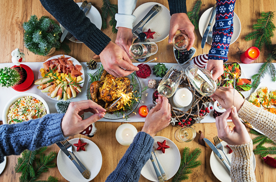 Baked turkey. Christmas dinner. The Christmas table is served with a turkey, decorated with bright tinsel and candles. Fried chicken, table.  Family dinner. Top view, hands in the frame
