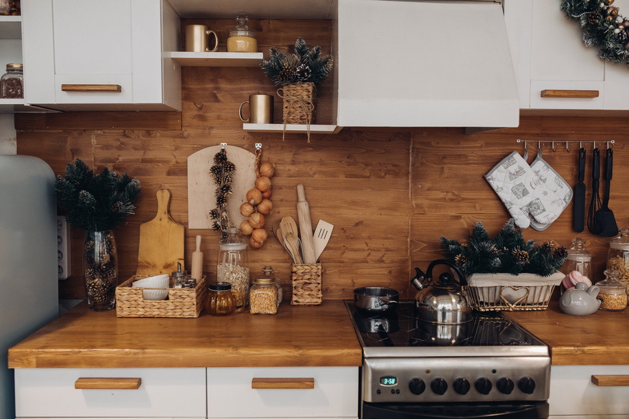 Close-up of modern cozy kitchen in white and brown colors with stuff, cooker and decorative fir tree branches. Christmas decorations.
