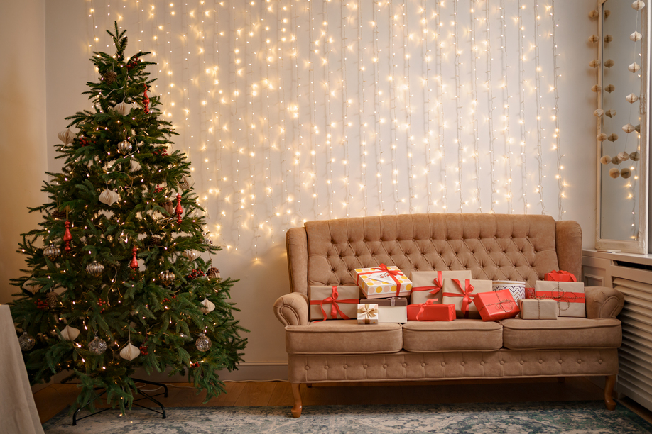 Festive interior with many presents on comfortable sofa and decorated Christmas tree